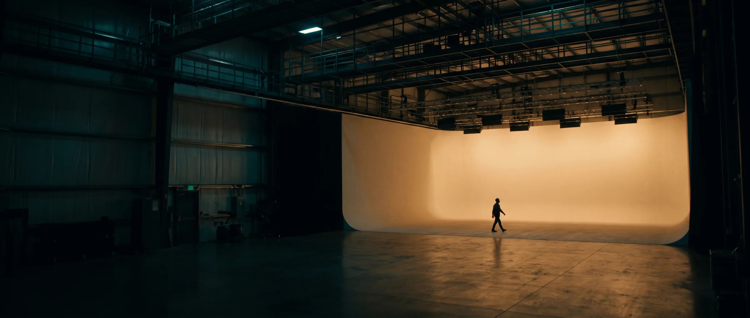 An empty New Jersey soundstage at blue hour, cyclorama lit and lighting grid overhead — production infrastructure